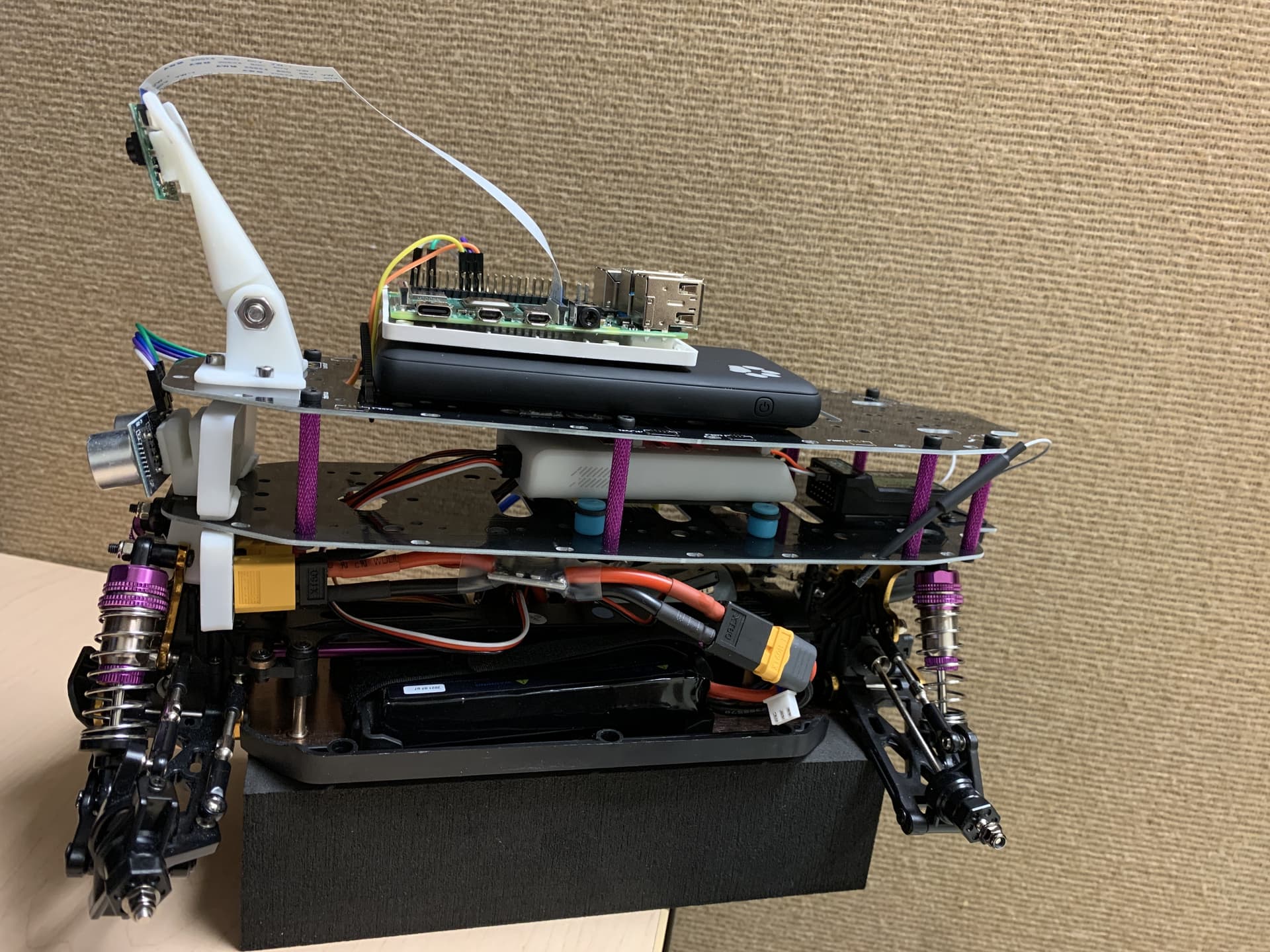 Course RC platform with a raised camera, Raspberry Pi, ultrasonic sensor, and stacked electronics.